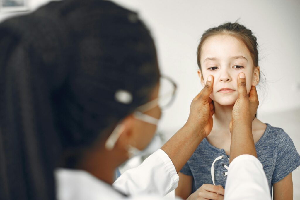 A female doctor carefully examines a young girl's face during a medical checkup.